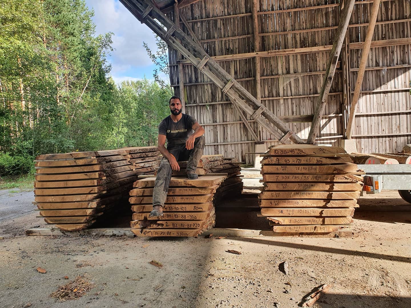 Andreas Asprou sitter på nysågade övergrova plank i ett lagerhus